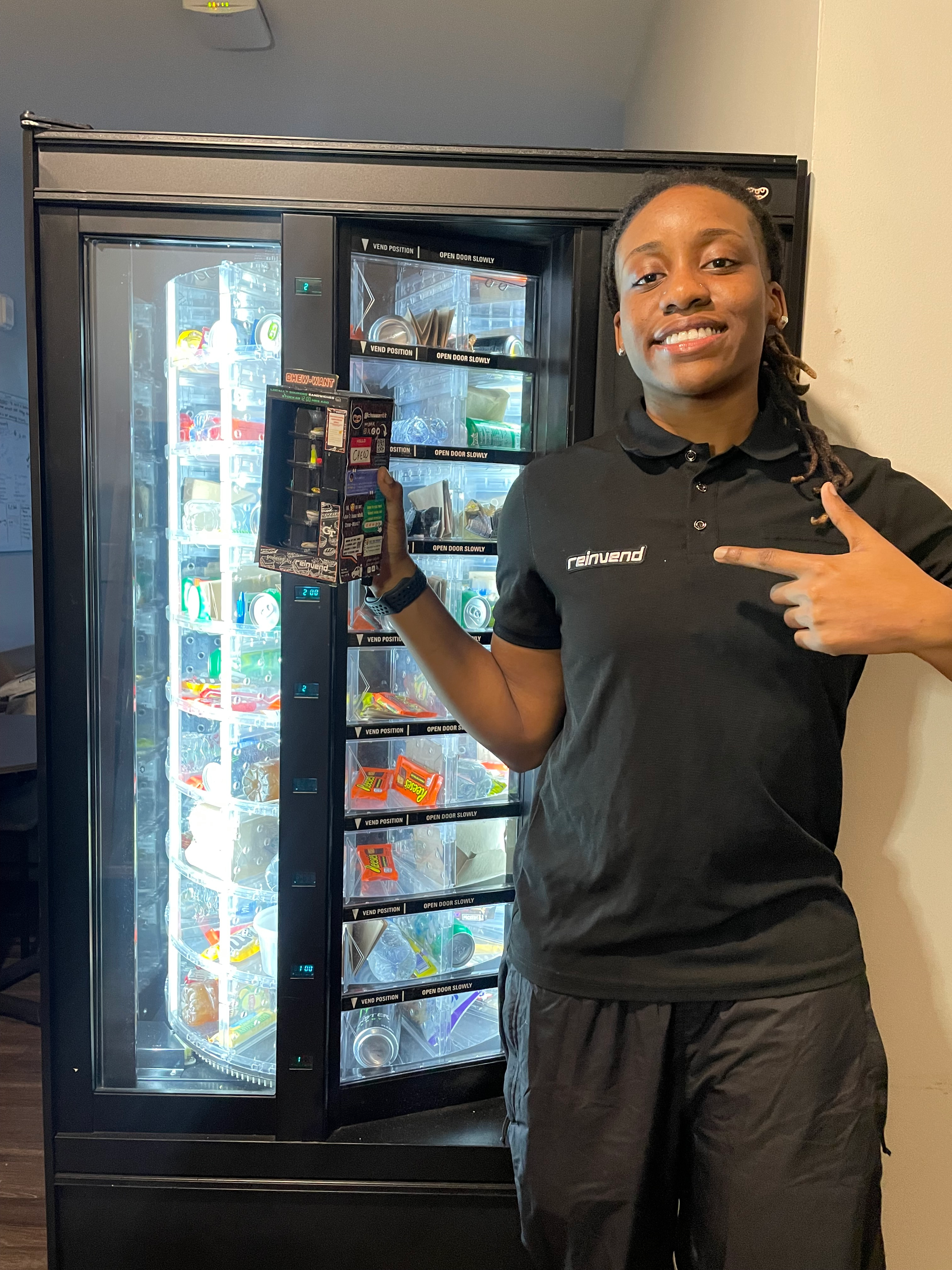 Co-founder Kiandra Peart poses with a prototype of Reinvend in front of a campus vending machine.